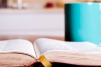 An open Bible lying beside a teal coffee mug on a table — Bible study at Immanuel Lutheran Church, Joplin, Missouri