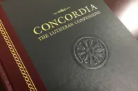 Concordia: The Lutheran Confessions, the black and gold hardcover from Concordia Publishing House, embossed with a Luther rose and resting on a wooden table